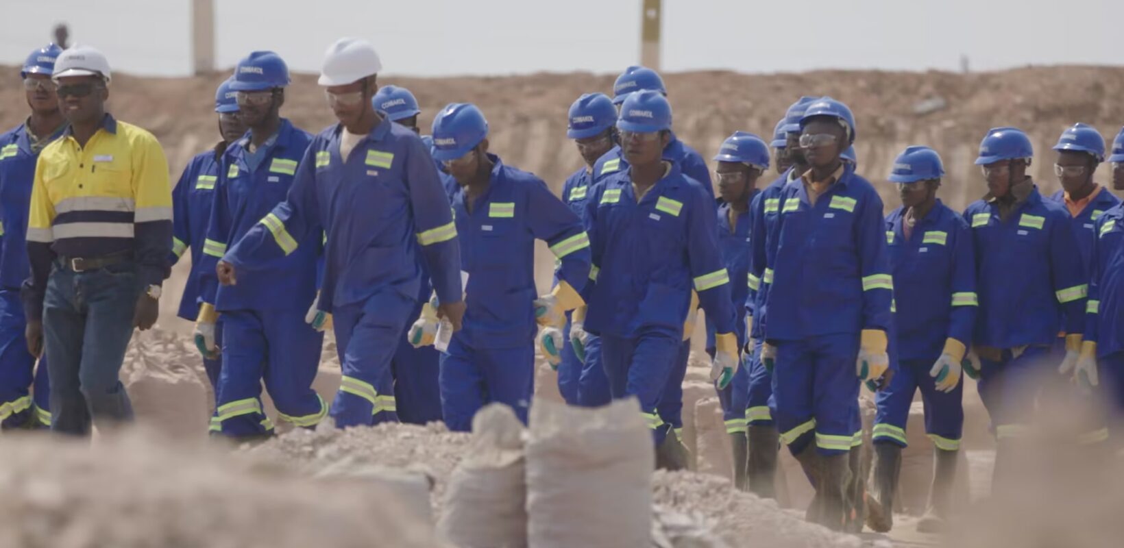 Group of people wearing blue boiler suits and hard hats
