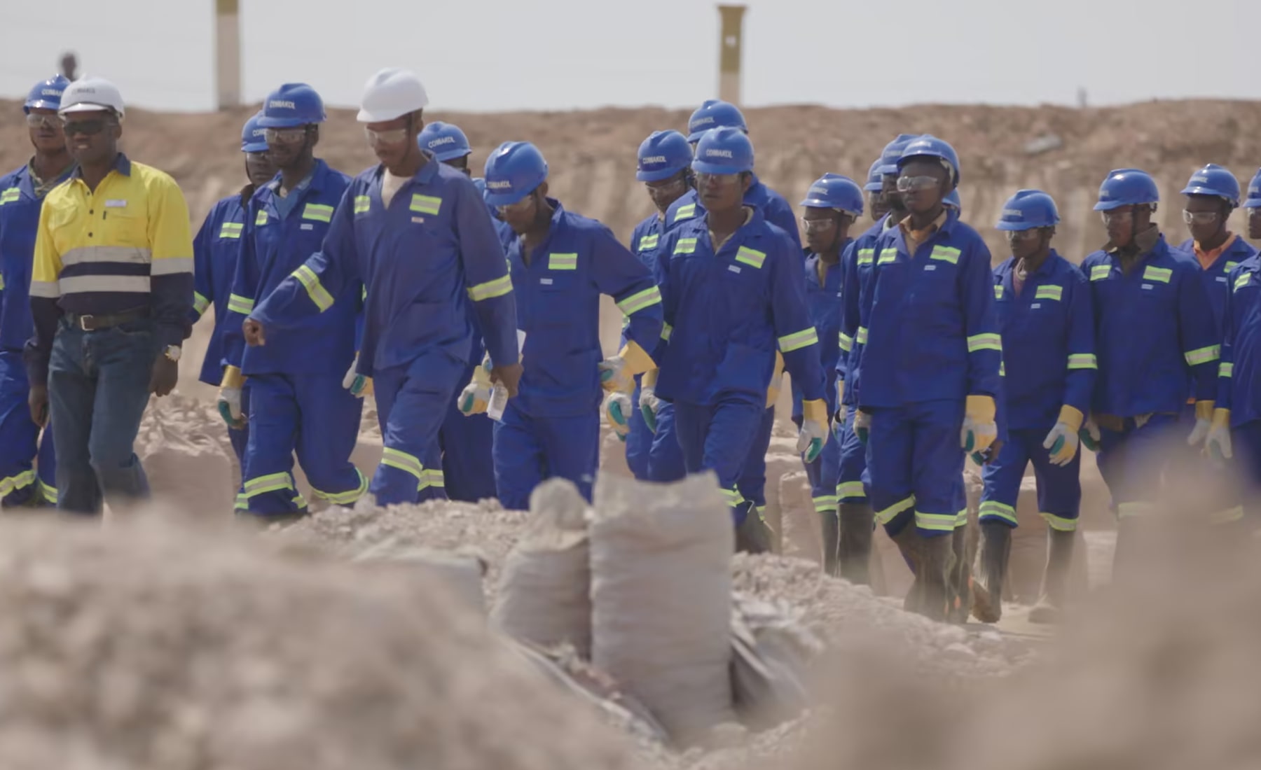 Group of people wearing blue boiler suits and hard hats