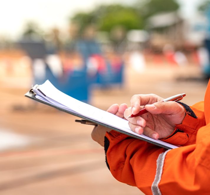 Person wearing an orange jacket holding a clipboard and pen