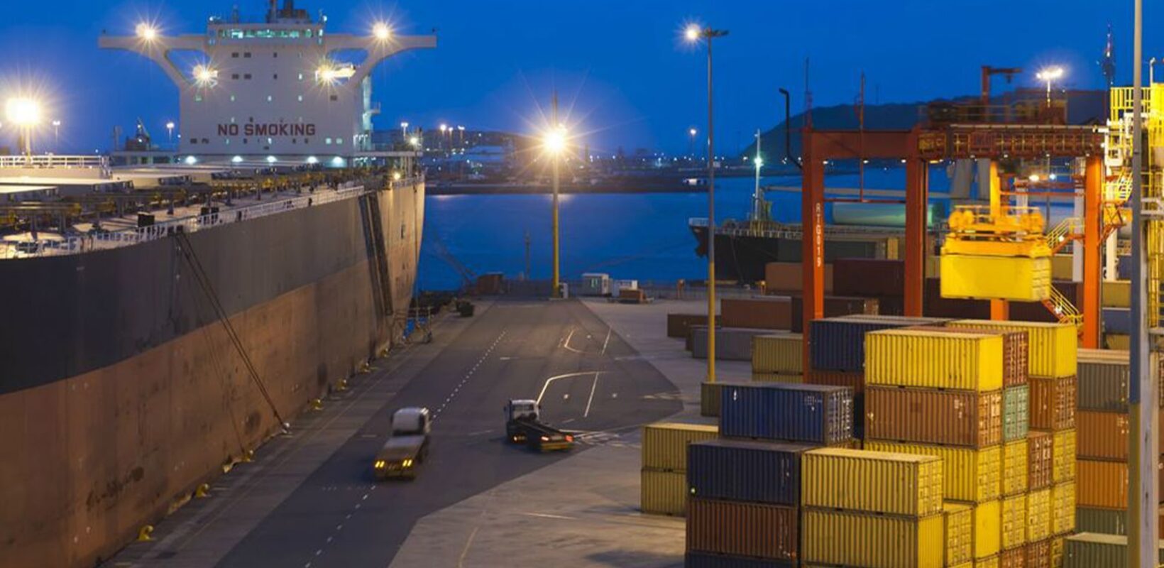 Shipping dock at night, with a ship and shipping containers
