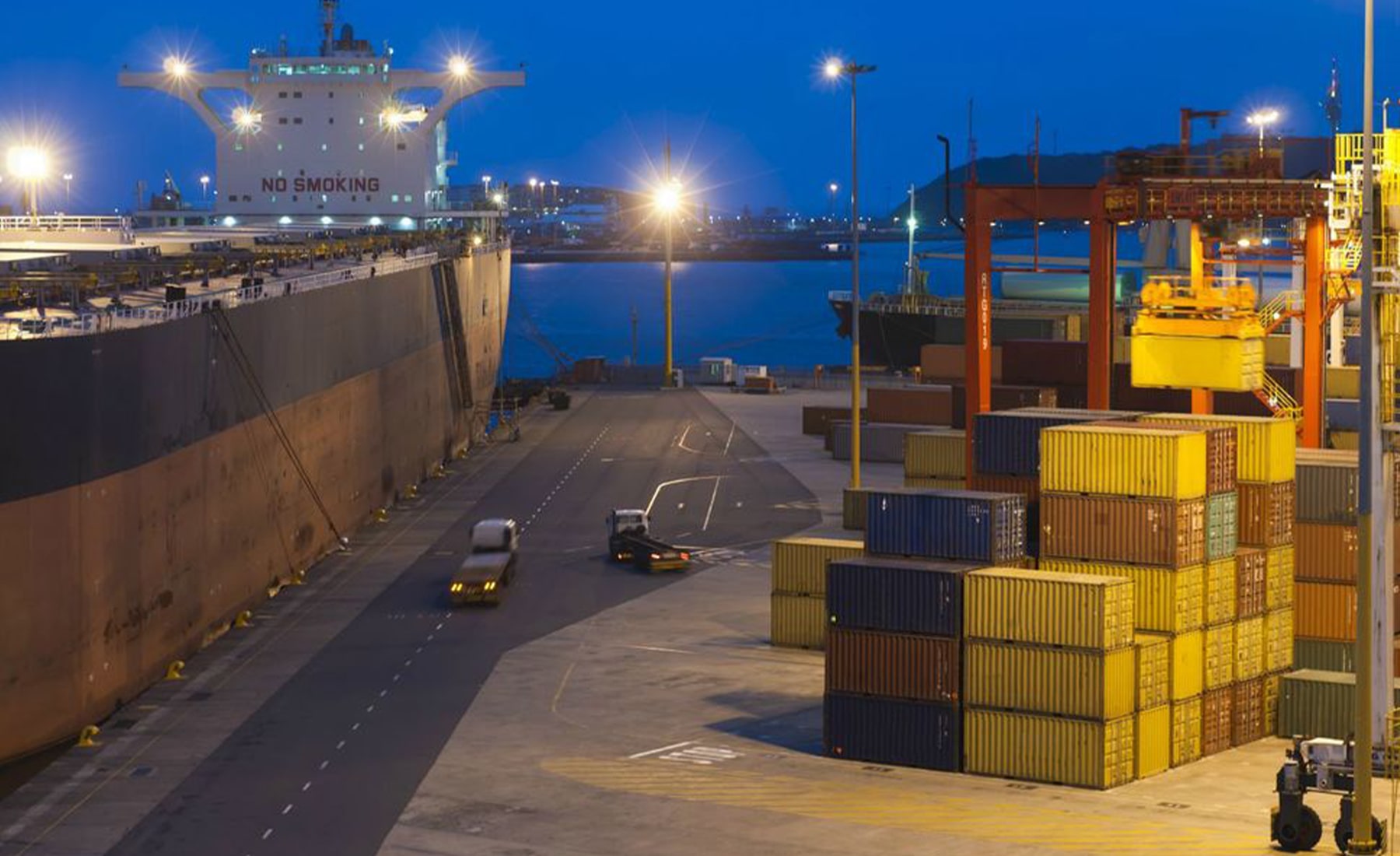 Shipping dock at night, with a ship and shipping containers