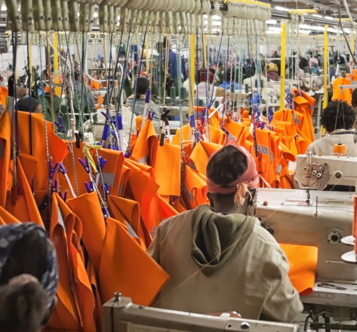 People working in a fabric factory with orange fabric and thread