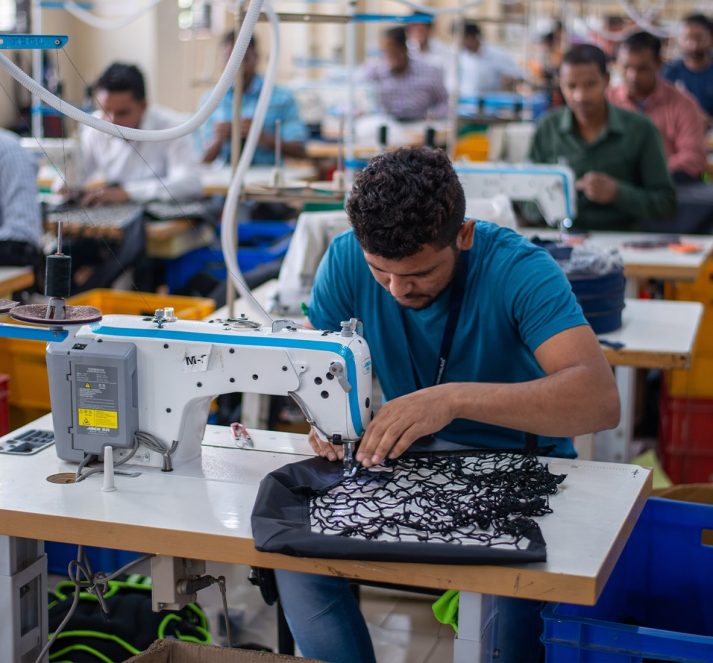 Men in fabric factory using sewing machines to create items of clothing