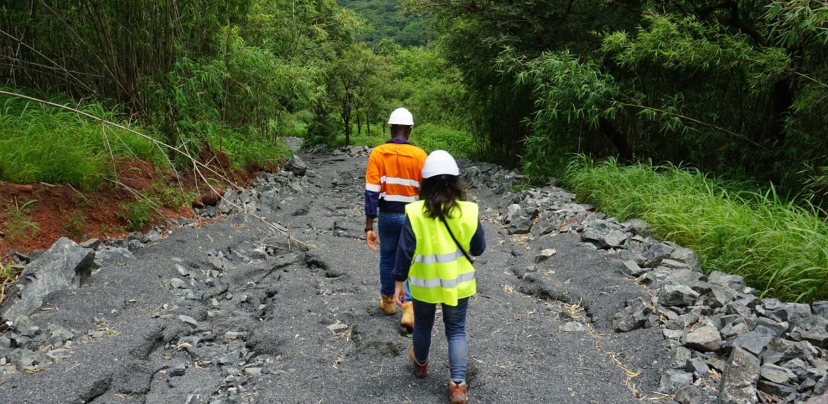 Male and female worker walking down a rocky pathway with trees and plants either side of the path