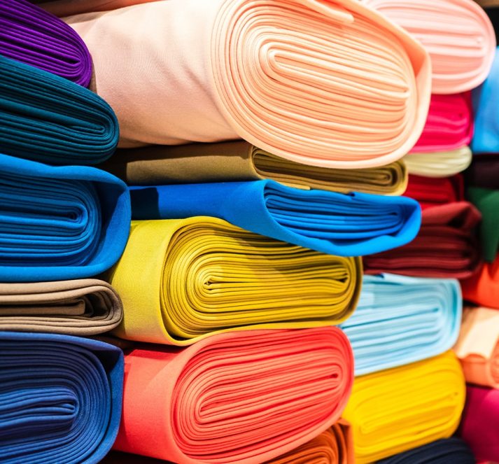 Multiple colours of fabric folded up and piled up on each other