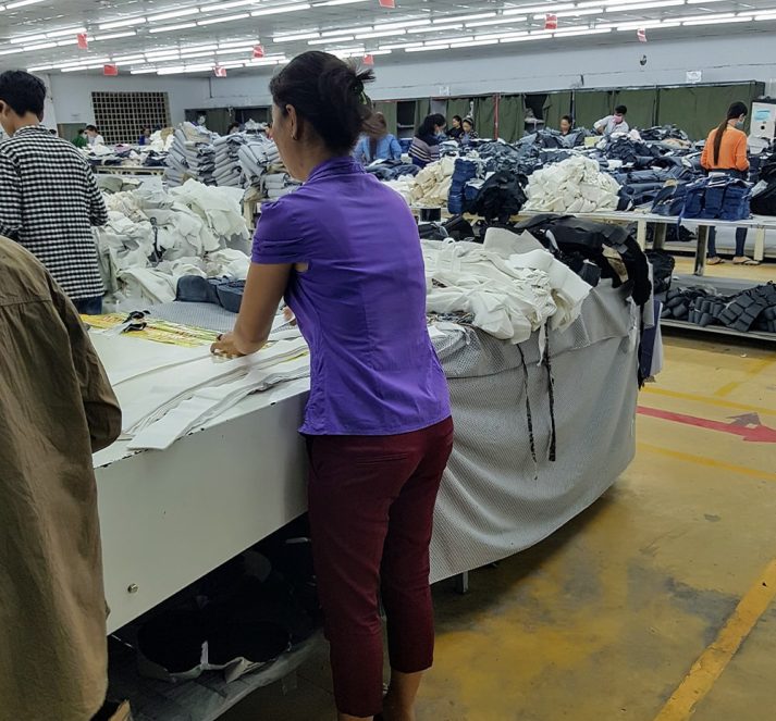 Woman in clothing factory measuring an cutting materials