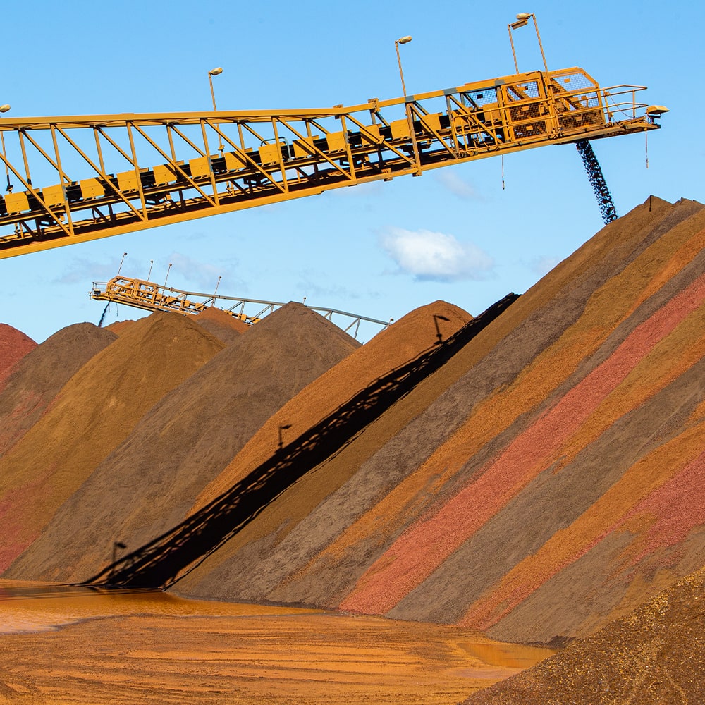 Large yellow machinery pouring mined materials into large piles