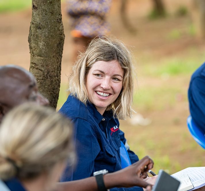 Fiona Hutmacher sat down smiling, with two people in the foreground blurred out