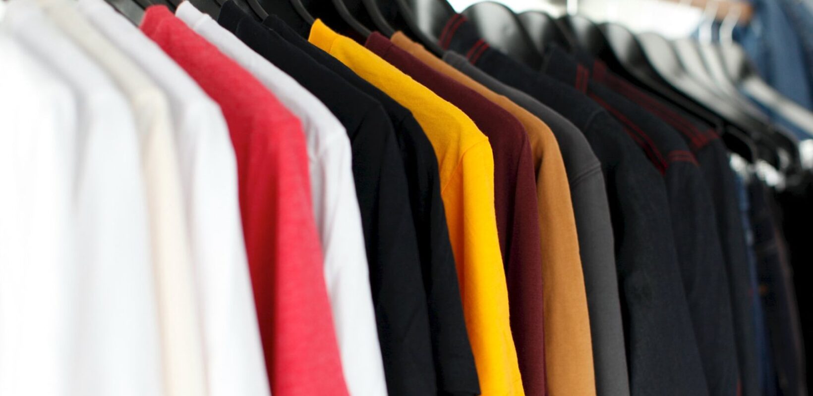Coloured t-shirts on hangers, hung up on a rail