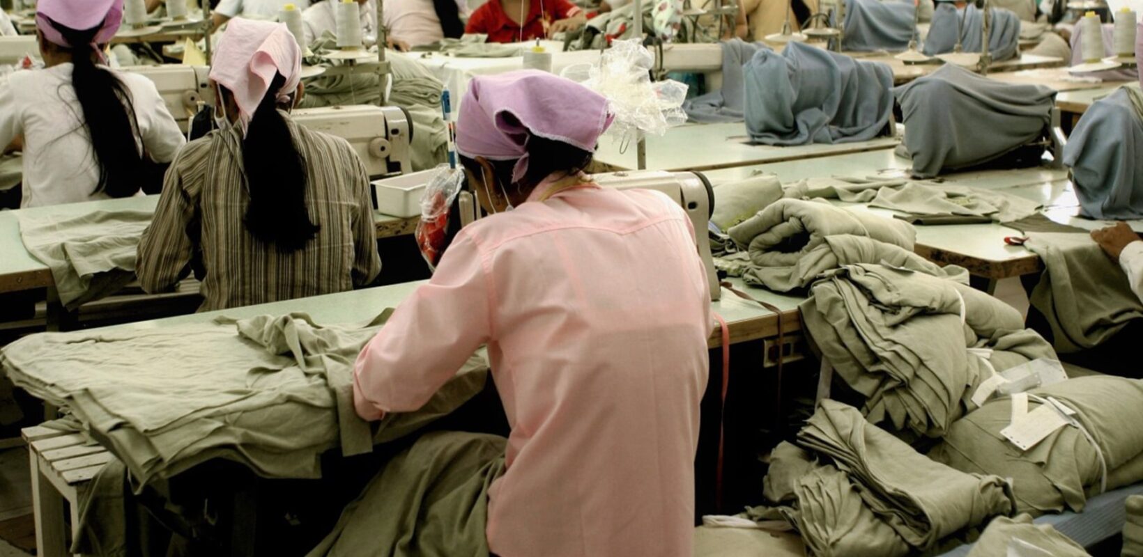 Woman in pink, working in a clothing factory using a sewing machine