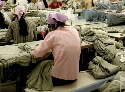 Woman in pink, working in a clothing factory using a sewing machine