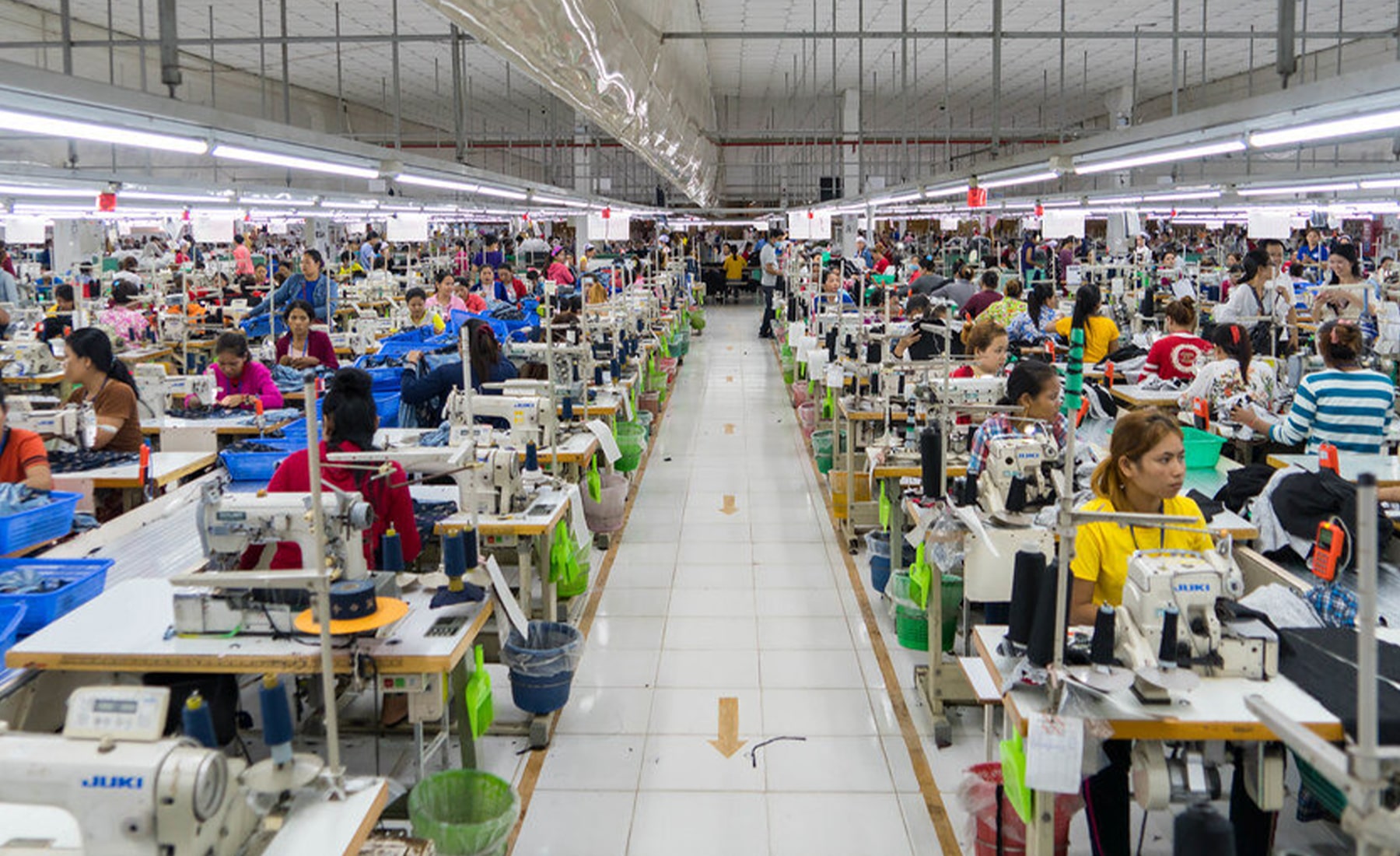 Clothing factor, with a woman wearing a face mask, whilst using a sewing machine at her desk