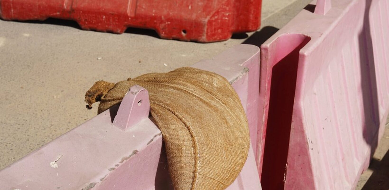 Sand bag on top of a red barrier
